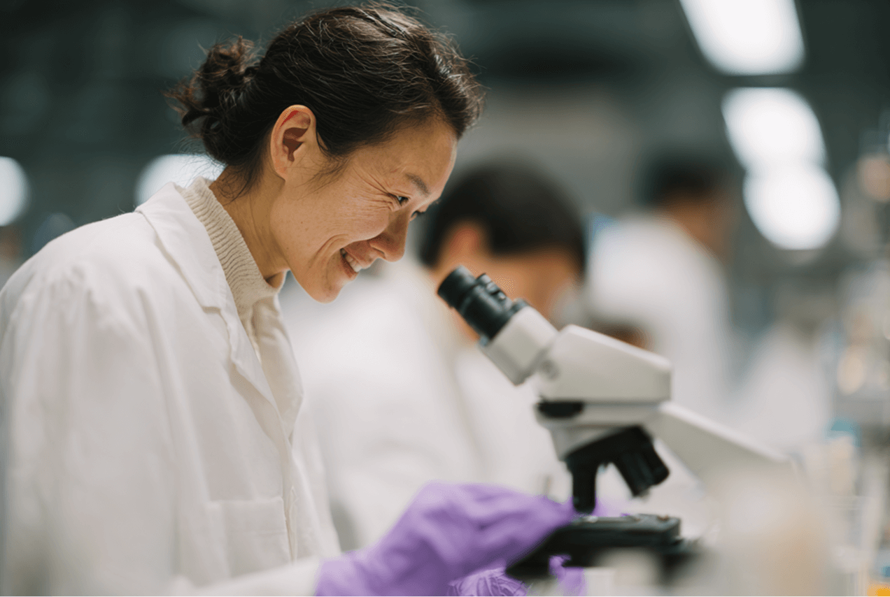 An image of a female scientist looking through a microscope. 
